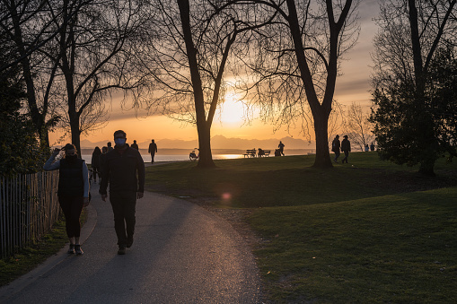 Seattle, USA - Apr 7, 2021: Sunset at Myrtle Edwards Park with people wearing masks getting exercise late in the day.
