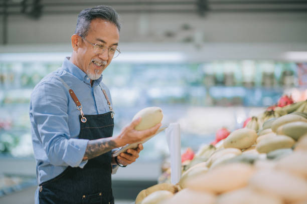istock asian chinese senior man examining mango fruit at his market stall with digital tablet 1321414067