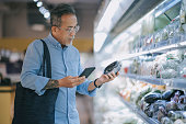 asian chinese senior man shopping in supermarket at refrigerated section for vegetable