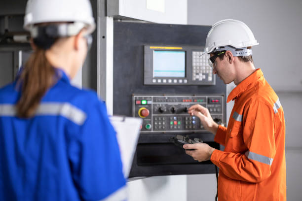 istock Caucasian white male and female engineer standing inspecting CNC machine operation. 1321420323