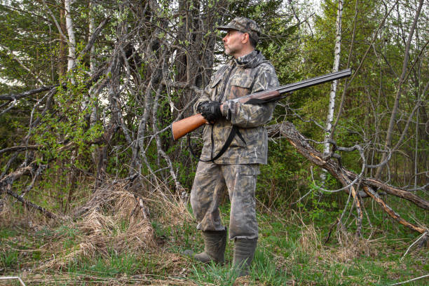 istock a hunter with a shotgun stands by a dead tree 1321423648
