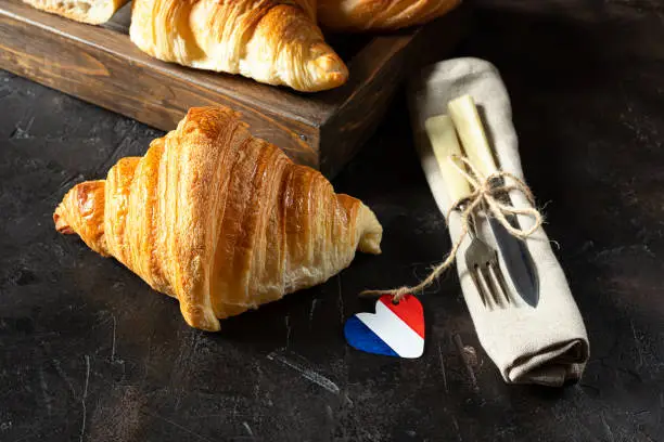 Photo of Croissants and cutlery on a dark table
