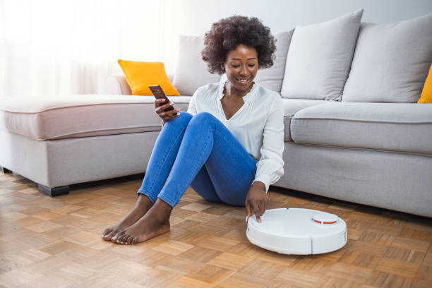 istock Girl turning on robot vacuum cleaner. 1321426277