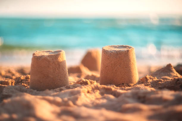 istock sand castle on the seashore against a backdrop of blurry blue waves. summer background 1321426394