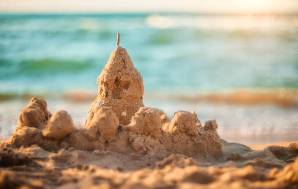 istock sand castle on the seashore against a backdrop of blurry blue waves. summer background 1321426395