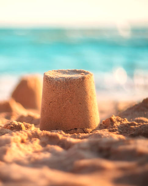 istock sand castle on the seashore against a backdrop of blurry blue waves. summer background 1321426410