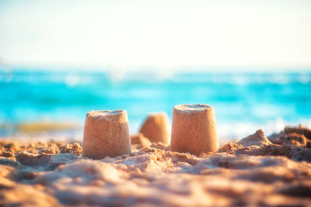 istock sand castle on the seashore against a backdrop of blurry blue waves. summer background 1321426420