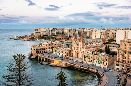 View of Balluta Bay and St Julians Bay from above in the twilight. The skyline is dominated by the Carmelite Parish Church (Church of Our Lady of Mont Carmel). In Sliema, Malta.