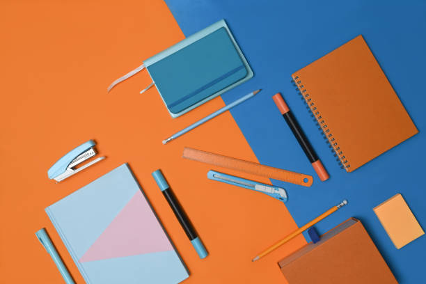 istock Notebook and stationery on two tone blue and orange background. 1321428539