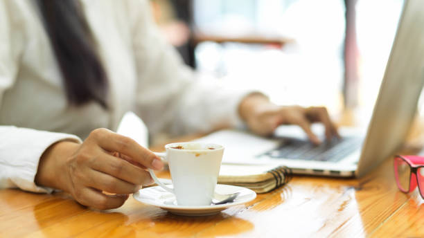 istock Close up view of female hand holding coffee cup while working with laptop 1321430656