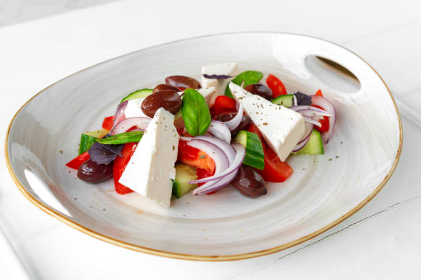 istock Greek salad in plate on white wooden background 1321431300