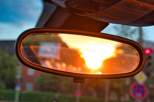 The sun dazzles in the rearview mirror while driving