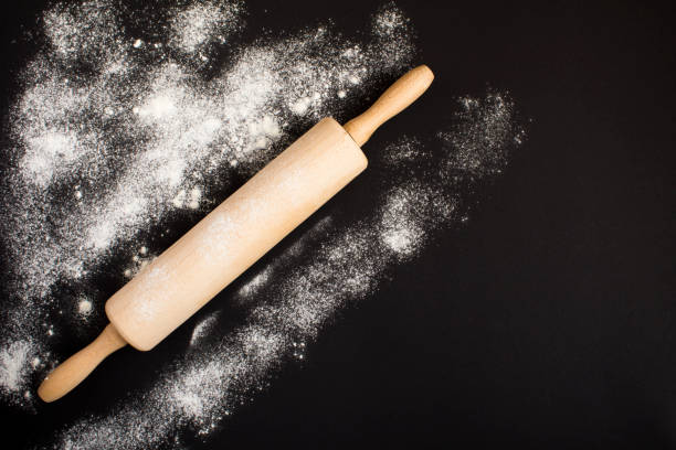istock Top view on rolling pin and white flour on dark surface. Kitchen background. 1321436135