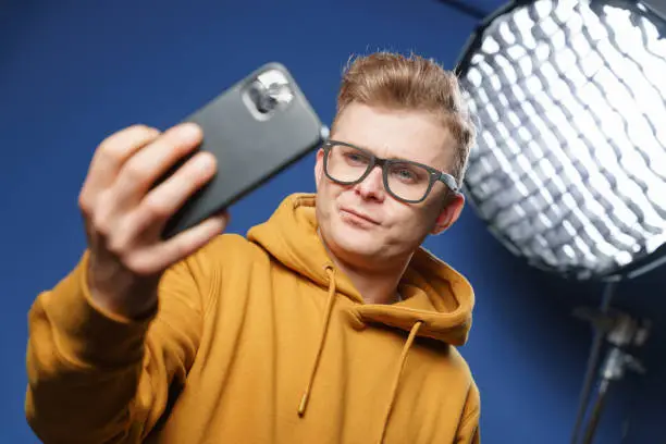 Photo of The vlogger records a video message on his phone to his subscribers and fans.