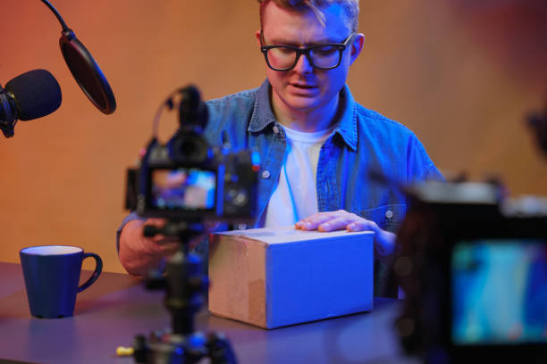 istock The vlogger in his studio is conducting a live stream, he is preparing to unpack the parcel that was delivered to him from the online store. 1321439579