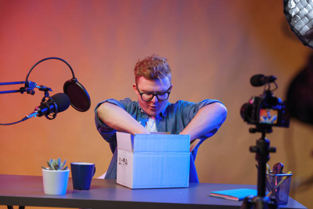 A blogger opens a package that has just been delivered to him from an online store.