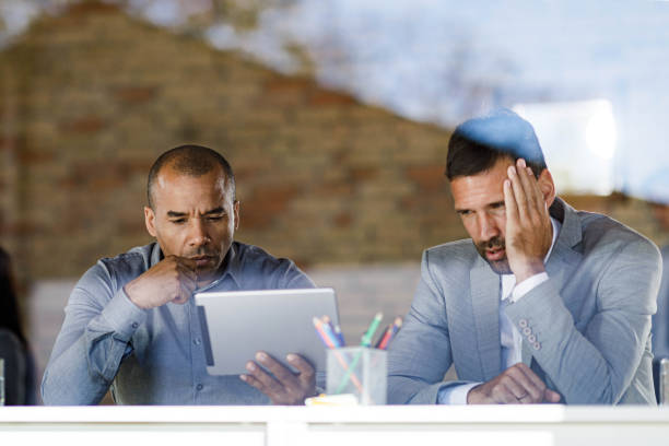 businessmen reading a problematic e-mail on a touchpad in the office. - looking through window businessman problems reading imagens e fotografias de stock