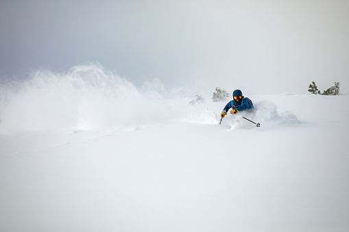 Off-piste skier riding down in deep powder snow