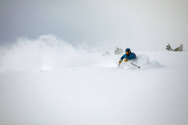 Off-piste skier riding down in deep powder snow Extreme skier riding down in fresh powder snow in cold winter day deep snow stock pictures, royalty-free photos & images