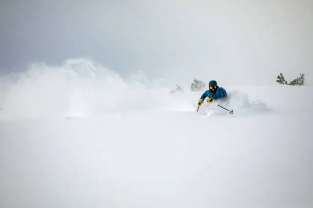 Photo of Off-piste skier riding down in deep powder snow