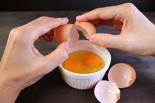Closeup man's hands cracking egg into a bowl
