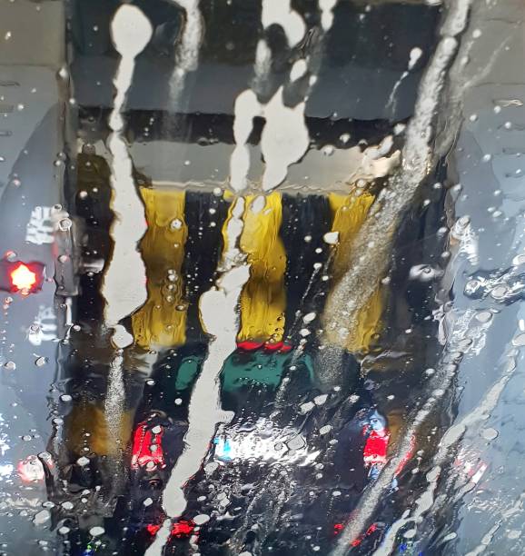 A car is washing in a car wash, a view through the wet windshield. The brushes washing a car in a car wash.