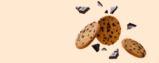 istock Tasty fresh biscuits and pieces of dark chocolate against bright yellow background.Empty space 1321446865