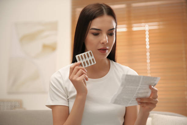 istock Young woman with pills reading medicine instruction at home 1321448024