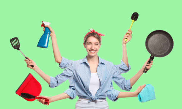 istock Multitask housewife with many hands holding different stuff on green background 1321448056