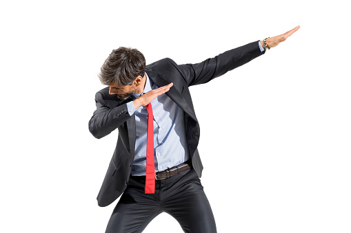 Businessman in suit doing a dab dance pose with slanted inclined arms and head down in a three-quarter frontal portrait isolated over a white studio background