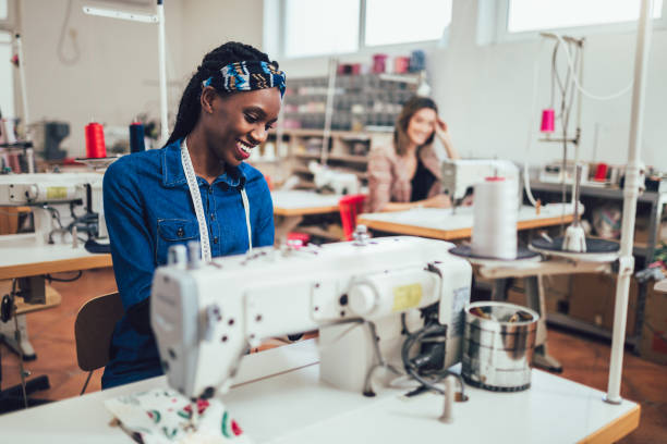 istock Young african fashion designer using sewing machine in her workshop 1321449411