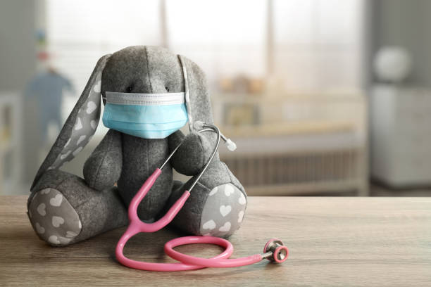 istock Toy bunny with protective mask and stethoscope on wooden table indoors, space for text. Pediatrician practice 1321451179
