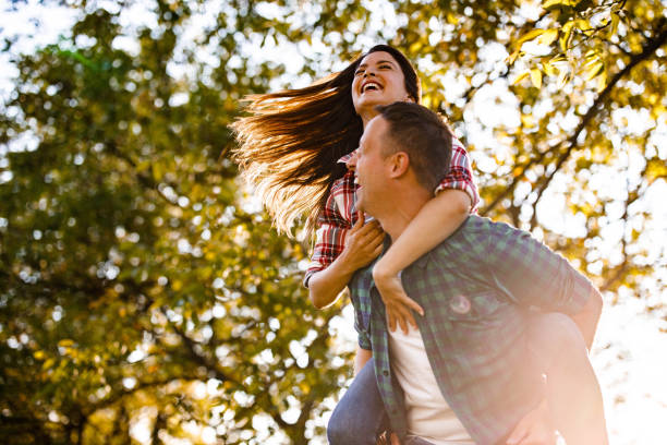 istock Playful couple having fun while piggybacking during spring day in forest. 1321451755