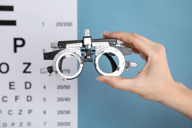istock Woman holding trial frame against eye chart test on blue background, closeup. Ophthalmologist tool 1321452681
