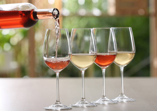 verter vino rosado de botella en vaso sobre mesa sobre fondo borroso - wine pouring wineglass white wine fotografías e imágenes de stock