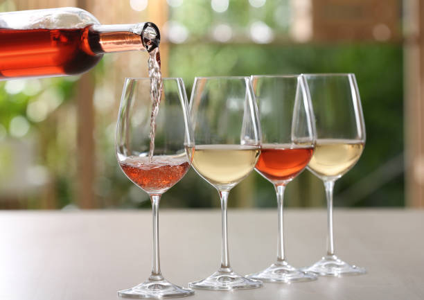 istock Pouring rose wine from bottle into glass on table against blurred background 1321452934