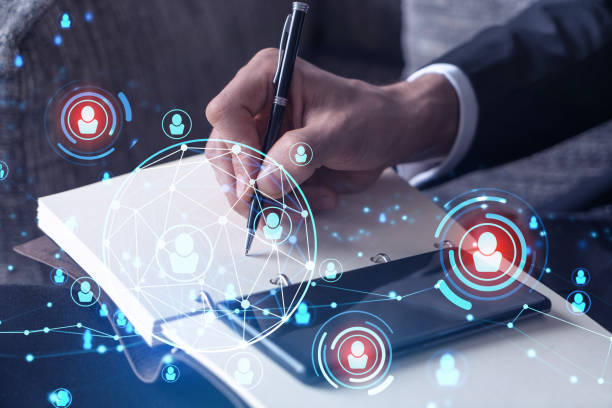 istock HR specialist is taking notes concerning new candidates to create international network in recruitment process. Checking social media connections in smartphone. Hologram icons. Formal suit 1321454531