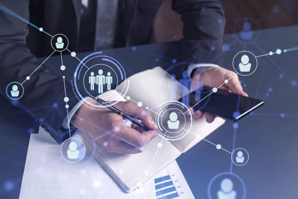 istock HR specialist is taking notes concerning new candidates to create international network in recruitment process. Checking social media connections in smartphone. Hologram icons. Formal suit 1321454675
