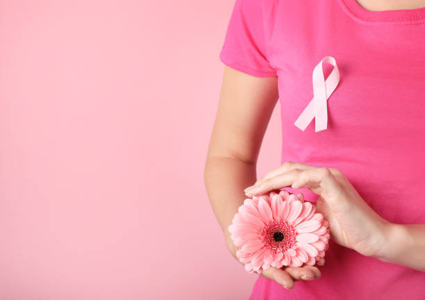 belle fleur rose dans les mains sur fond rose, concept de cancer du sein - octobre photos et images de collection