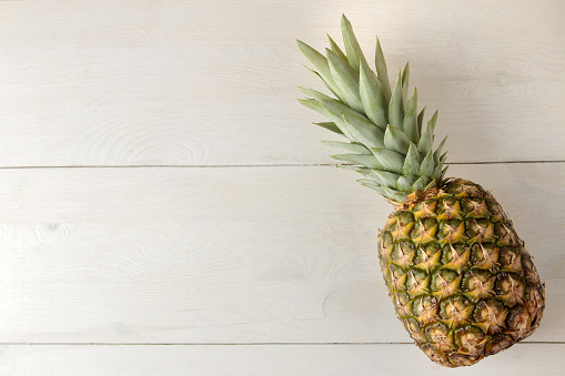 Ripe pineapple fruit on a white wooden table. summer. top view. space for text
