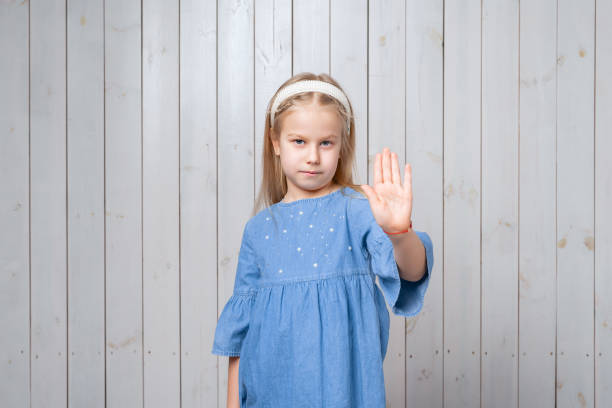 istock Serious little girl keeps palm forward at camera, makes forbid sign, restricts or warns, extends arm in stop sign 1321455988