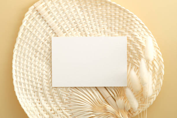 istock White invitation card mockup with lagurus on rattan fan on beige backround. Flat lay, top view, minimal style. 1321456821