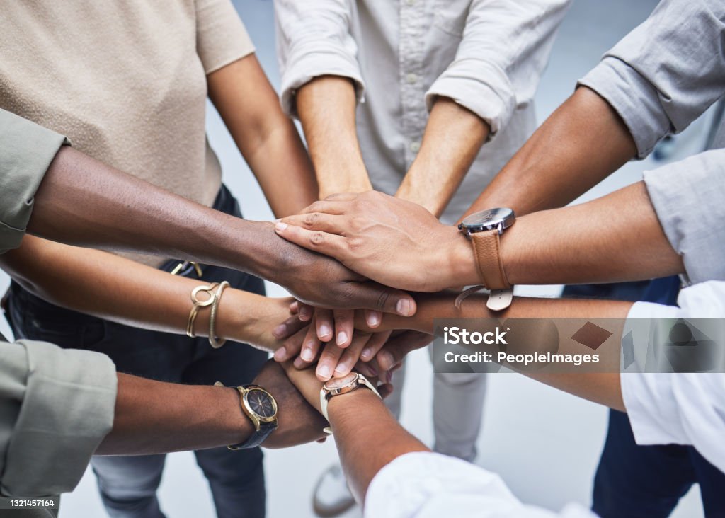 High angle shot of a group of unrecognisable businesspeople joining their hands together in a huddle Teamwork is at the fore of success Community Stock Photo