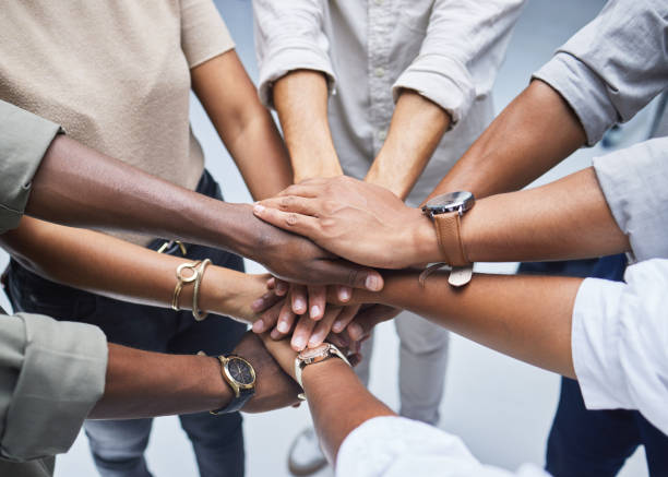 high angle shot of a group of unrecognisable businesspeople joining their hands together in a huddle - determination imagens e fotografias de stock