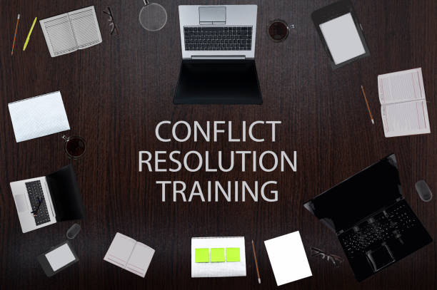 istock Top view of conflict resolution training text on the table with laptops, notepad, coffee, eyeglasses, pens. Business concept. 1321458873