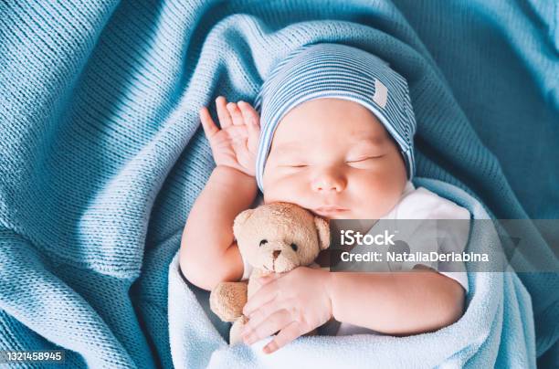 Newborn Baby Sleep At First Days Of Life Portrait Of New Born Child Boy One Week Old Sleeping Peacefully With A Cute Soft Toy In Crib In Cloth Background Stock Photo - Download Image Now