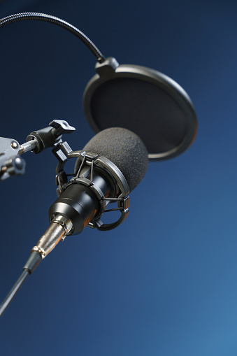 Close-up of a black microphone with an arm on a stand on a dark blue background