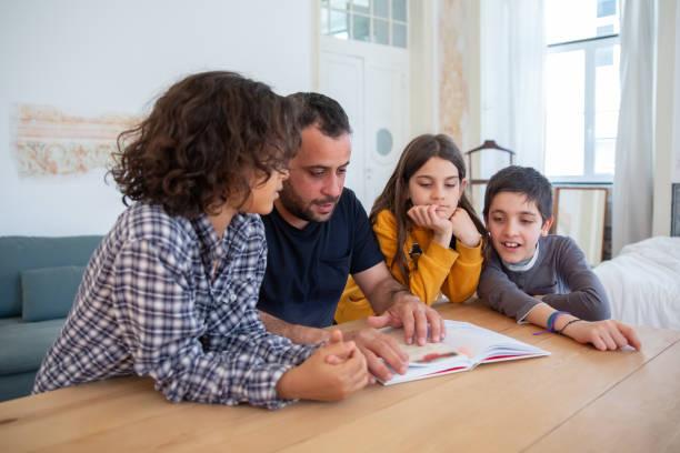 istock Serious dad sitting at table with kids and reading book 1321459979