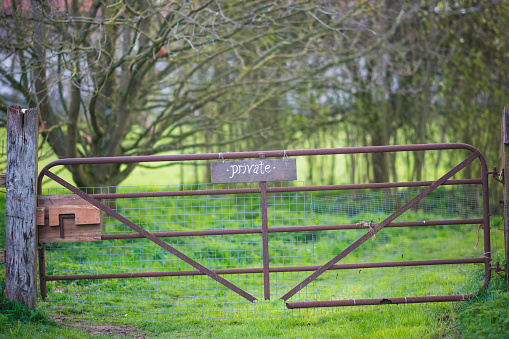 A rusty metal farm gate with a private sign in English countryside, Norfolk