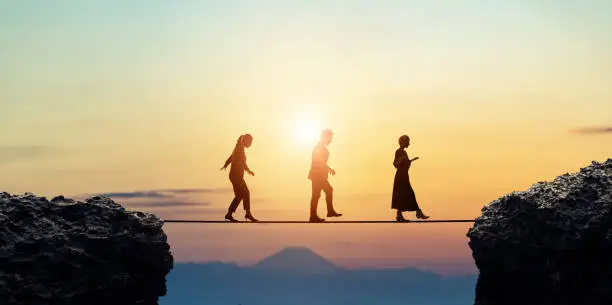 Photo of Group of businessperson walking on a tightrope. Risk management.